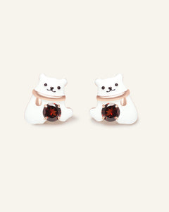 Polar Bear Garnet Studs in rose gold, resting on a warm linen background