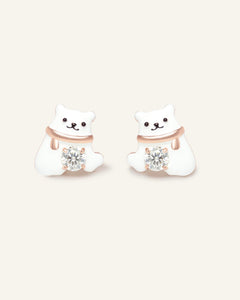 Polar Bear Moissanite Studs in rose gold, resting on a warm linen background
