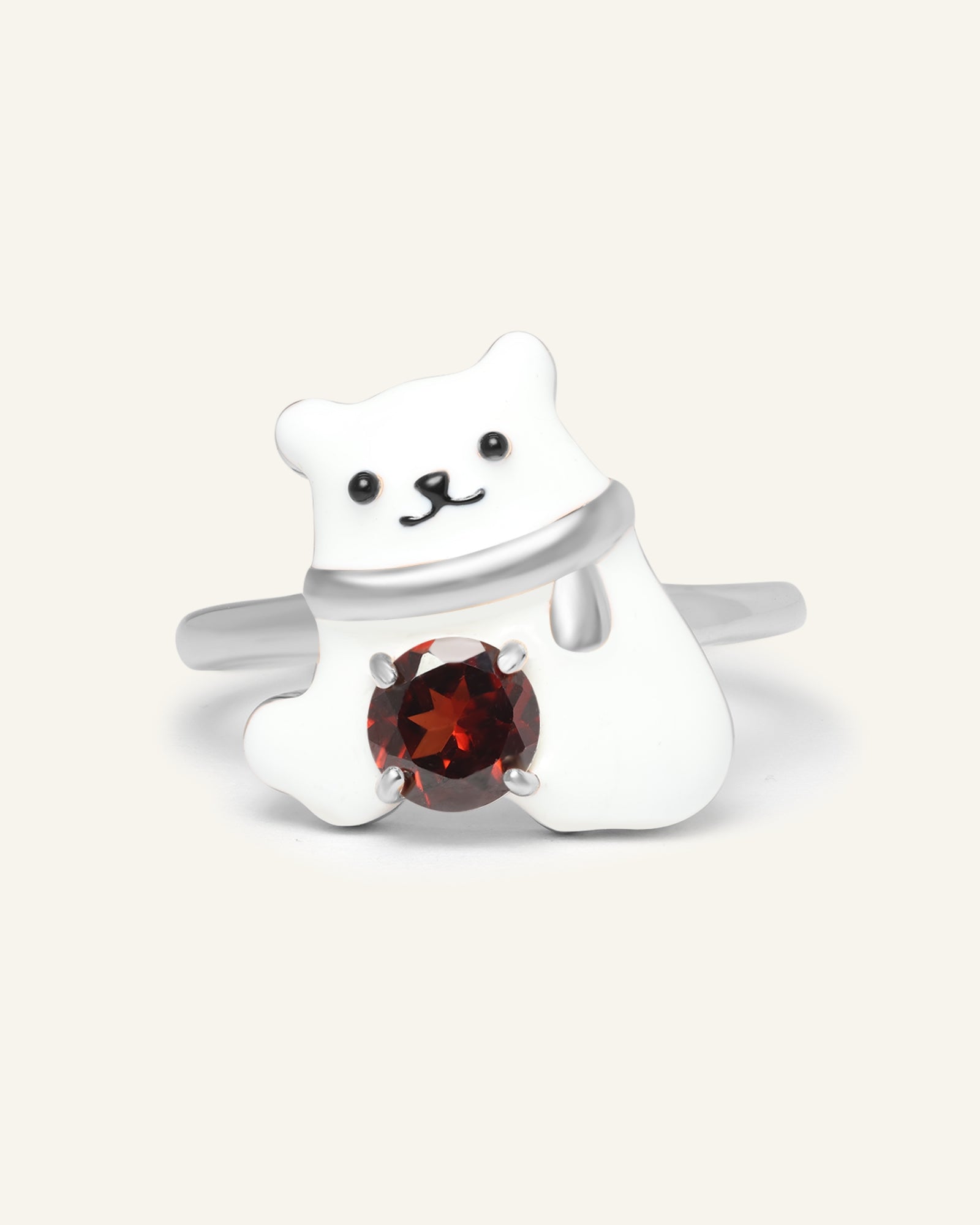 Polar Bear Garnet Ring in silver, resting on a warm linen background