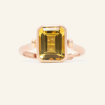 A rose gold ring featuring a reversible rectangular citrine gemstone adorned with intricate carvings and surrounded by cubic zirconias.