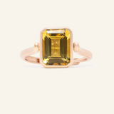 A rose gold ring featuring a reversible rectangular citrine gemstone adorned with intricate carvings and surrounded by cubic zirconias.