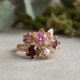 Lifestyle shot of the Rosette Floral Cluster Ring on a model with a blurred garden flower background.