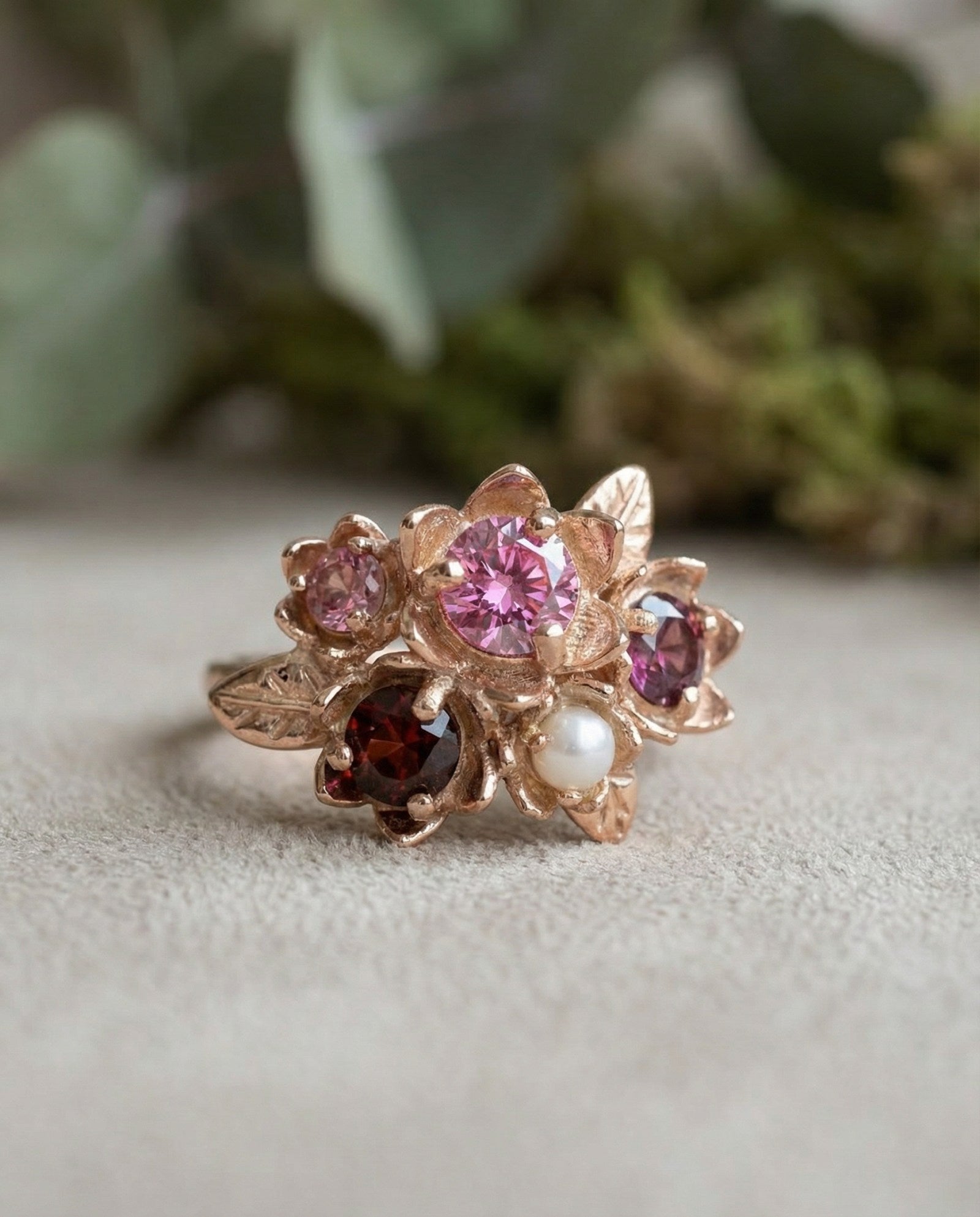 Lifestyle shot of the Rosette Floral Cluster Ring on a model with a blurred garden flower background.