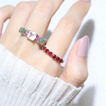 A model wearing the ruby half eternity band. The ring features a series of vibrant, deep red round-cut rubies set in a silver band, arranged in a continuous line around half of the band, showcasing a timeless and elegant design.