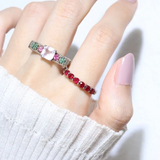 A model wearing the ruby half eternity band. The ring features a series of vibrant, deep red round-cut rubies set in a silver band, arranged in a continuous line around half of the band, showcasing a timeless and elegant design.