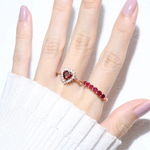 A model wearing the ruby half eternity band. The ring features a series of vibrant, deep red round-cut rubies set in a rose gold band, arranged in a continuous line around half of the band, showcasing a timeless and elegant design.
