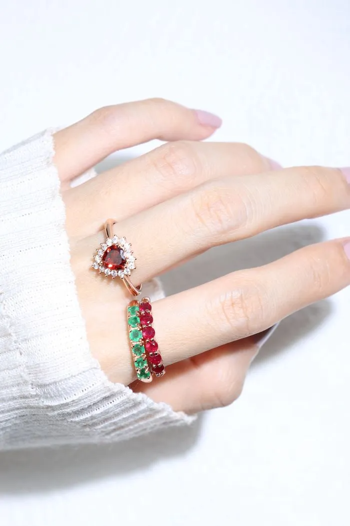 A model wearing the ruby half eternity band. The ring features a series of vibrant, deep red round-cut rubies set in a rose gold band, arranged in a continuous line around half of the band, showcasing a timeless and elegant design.