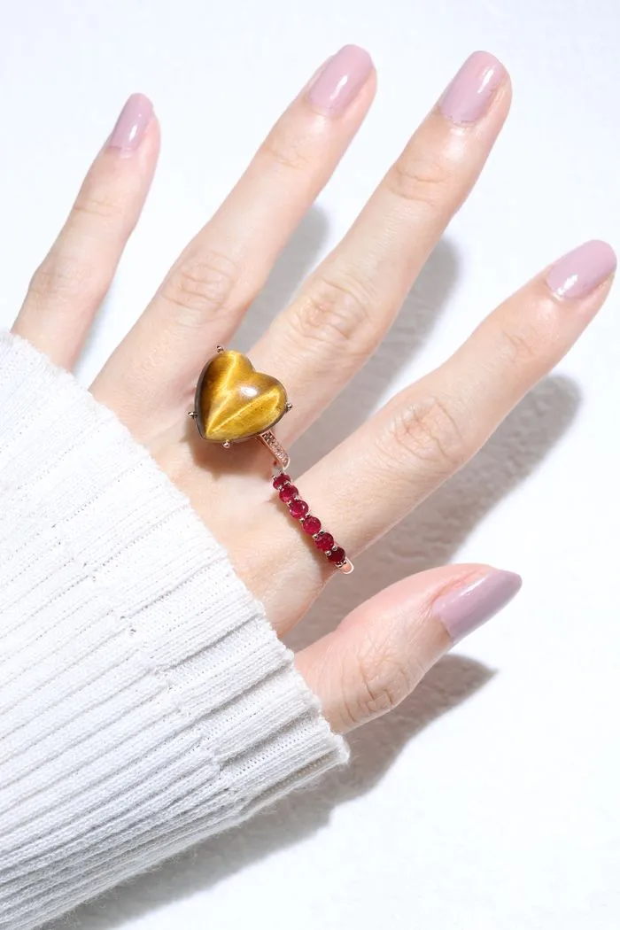 A model wearing the ruby half eternity band. The ring features a series of vibrant, deep red round-cut rubies set in a rose gold band, arranged in a continuous line around half of the band, showcasing a timeless and elegant design.
