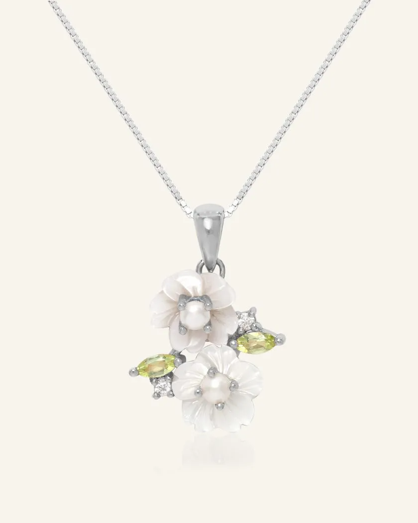 Sakura Blossom Necklace in silver, featuring hand-carved mother-of-pearl flowers, adorned with freshwater pearls and vibrant peridot accents, set in a delicate design.