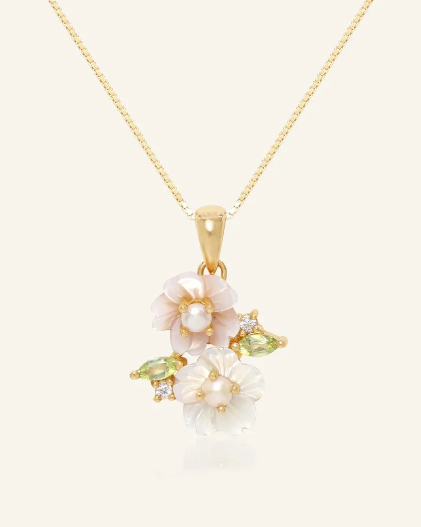 Sakura Blossom Necklace in yellow gold, featuring hand-carved mother-of-pearl flowers, adorned with freshwater pearls and vibrant peridot accents, set in a delicate design.