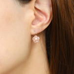 A model wearing the rose gold sakura hook earrings featuring hand-carved rose quartz petals and a luminous freshwater pearl centerpiece.	