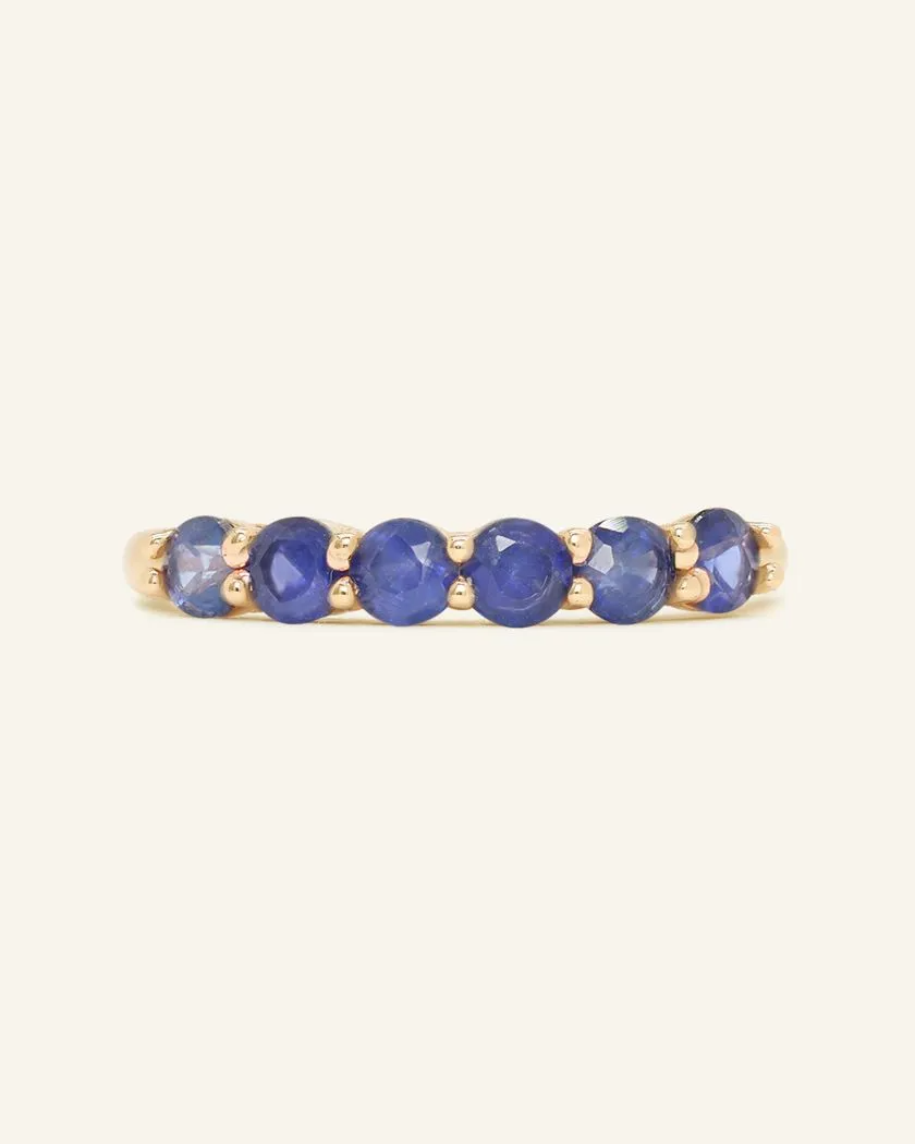 Yellow gold sapphire half eternity band featuring a row of vibrant round-cut blue sapphires in a classic prong setting, showcasing elegance and timeless beauty.