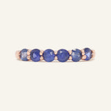 Sapphire Half Eternity Band in rose gold, resting on a warm linen background