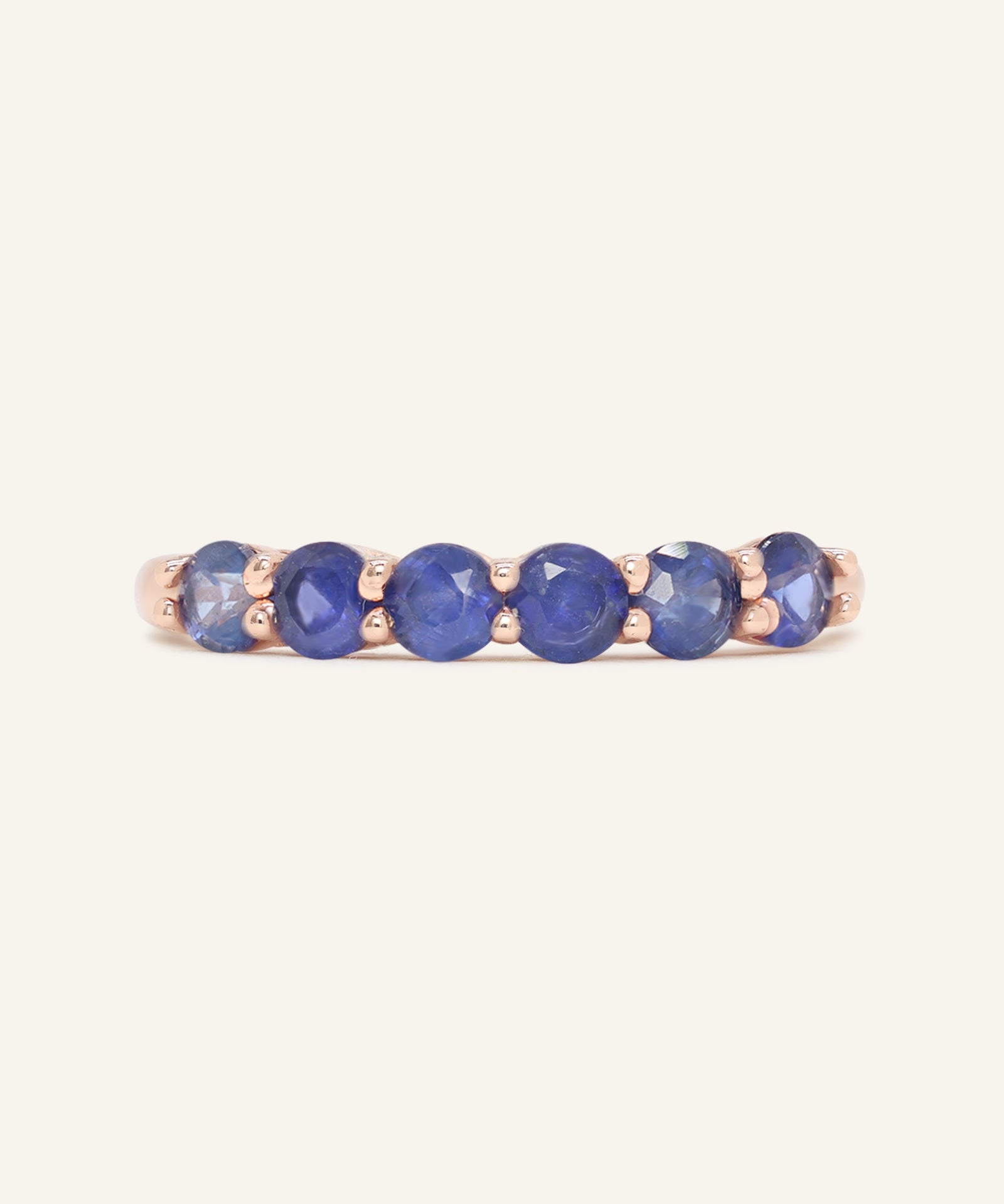 Sapphire Half Eternity Band in rose gold, resting on a warm linen background