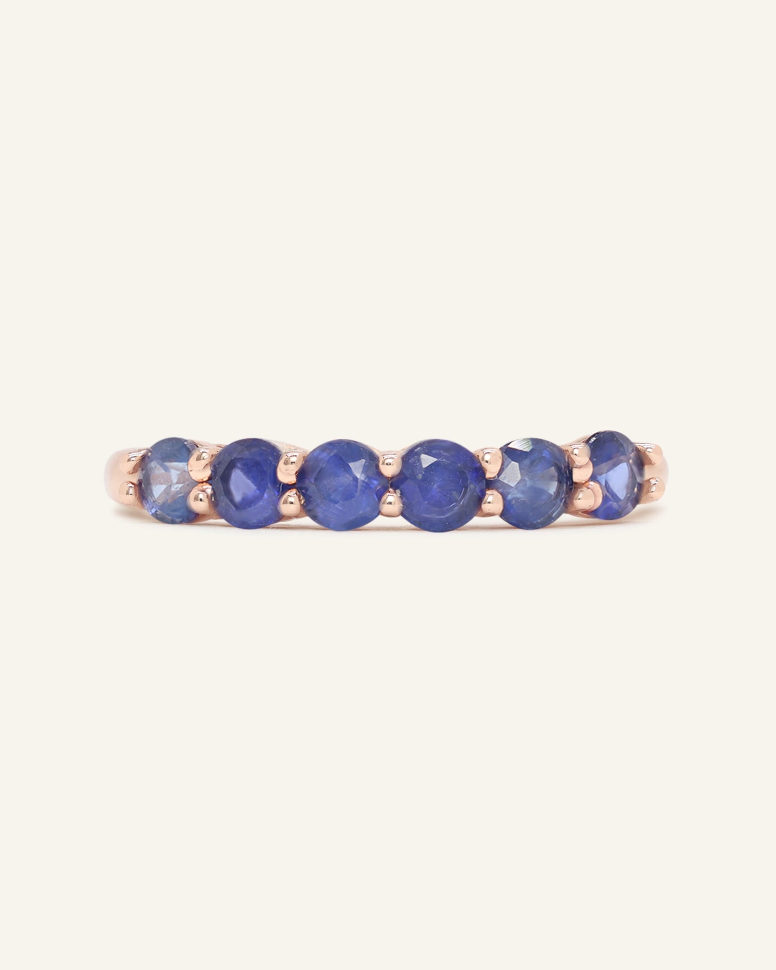 Sapphire Half Eternity Band in rose gold, resting on a warm linen background