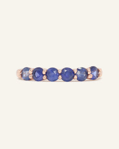Sapphire Half Eternity Band in rose gold, resting on a warm linen background