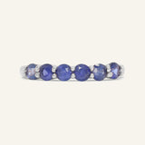Close-up of the Sapphire Half Eternity Band in silver, resting on a warm linen background