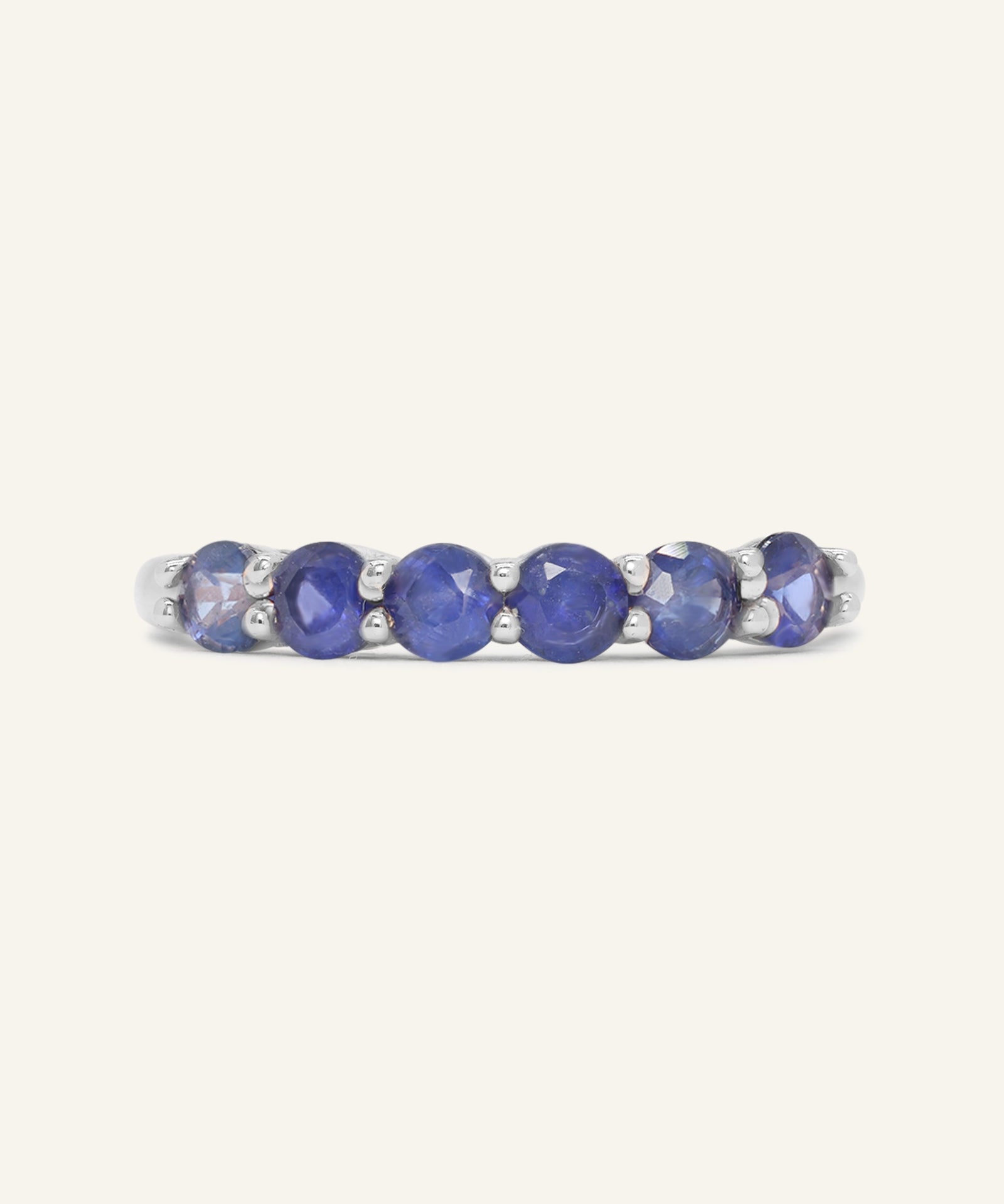 Close-up of the Sapphire Half Eternity Band in silver, resting on a warm linen background