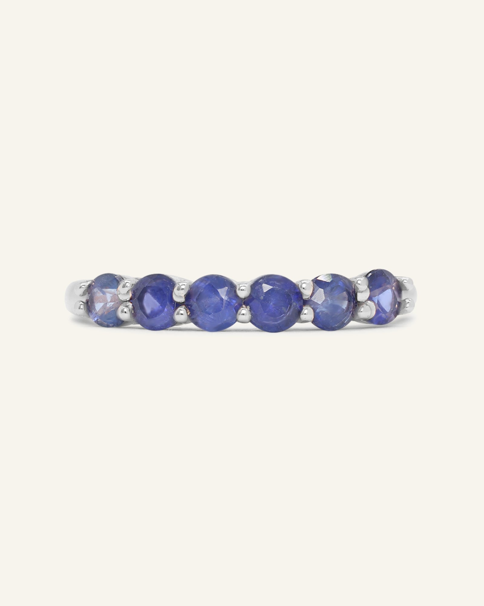 Close-up of the Sapphire Half Eternity Band in silver, resting on a warm linen background
