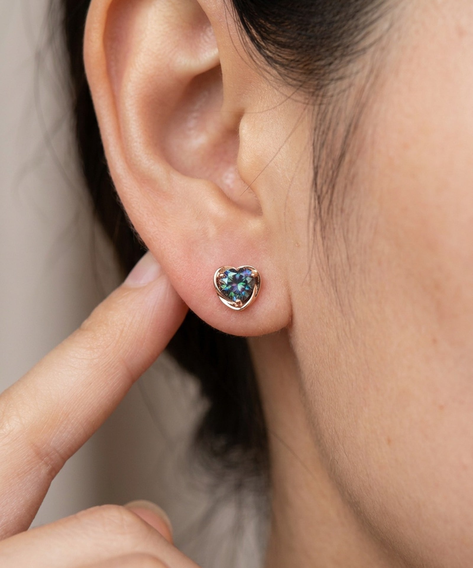 Model wearing Sculpted Heart Nest Moissanite Stud Earring in 18k rose gold vermeil with Celestial Teal center stone.