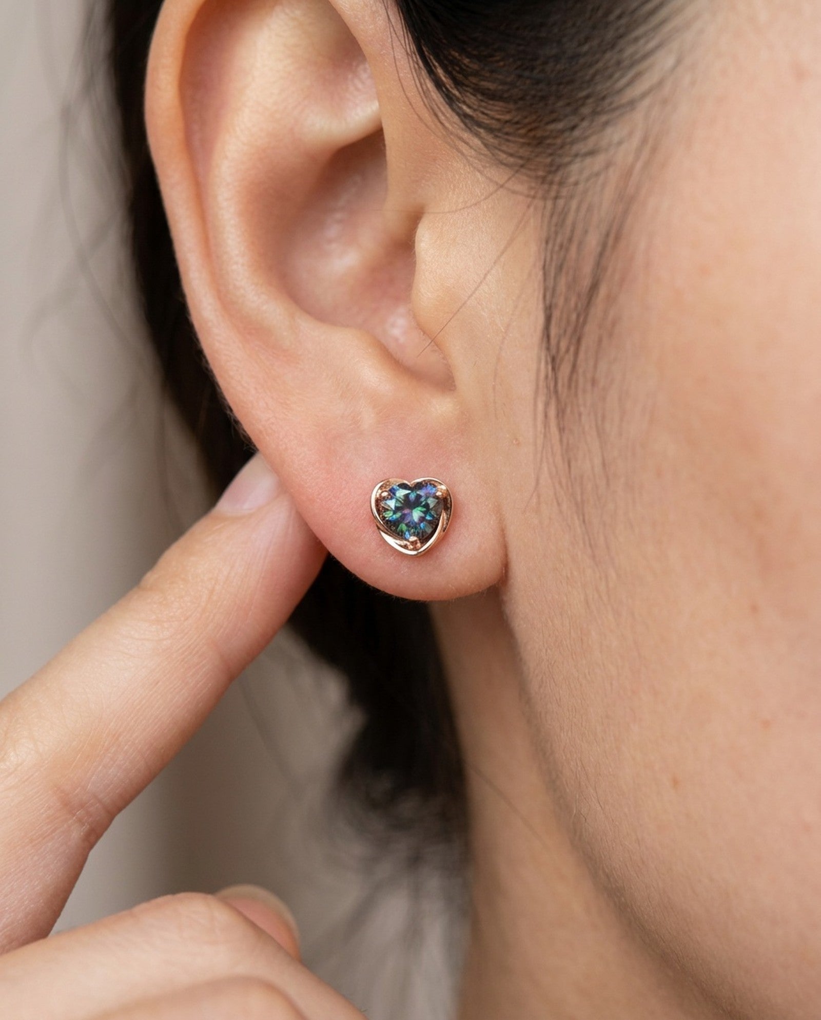 Model wearing Sculpted Heart Nest Moissanite Stud Earring in 18k rose gold vermeil with Celestial Teal center stone.