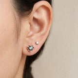 Ear stack featuring 18k rose gold Sculpted Heart Nest Moissanite Stud in Celestial Teal alongside a clear accent stud.