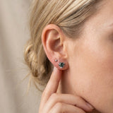 Model wearing sterling silver Sculpted Heart Nest Moissanite Stud in Celestial Teal paired with a small silver ball stud.