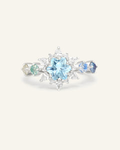 Close-up of the Starburst Snowflake Ring in silver, resting on a warm linen background