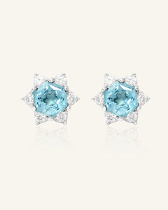 Close-up of the Snowflake Cut Studs | Sky Blue Topaz in silver, resting on a warm linen background