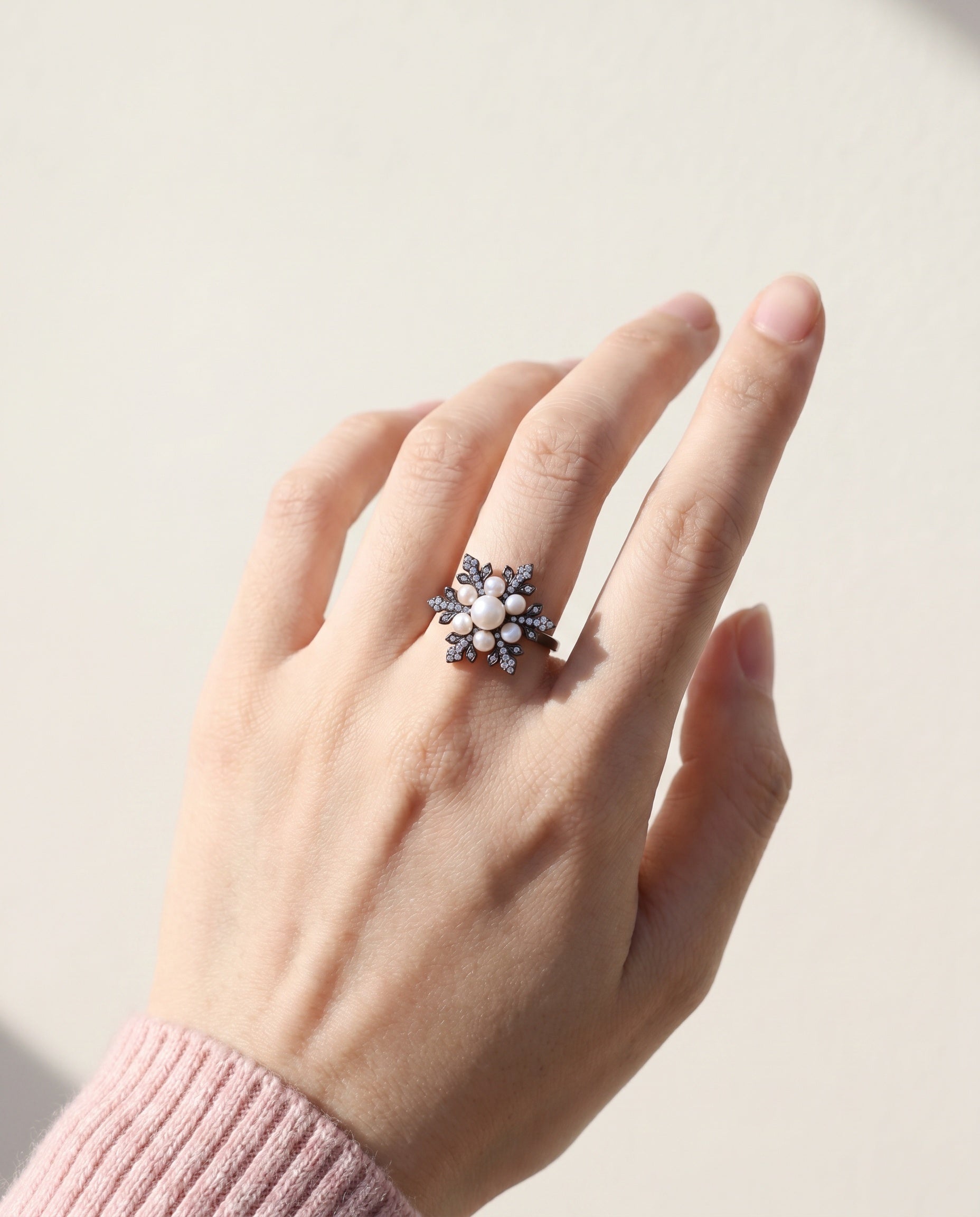 Snowflake Pearl Halo Ring in black gold, worn on a model