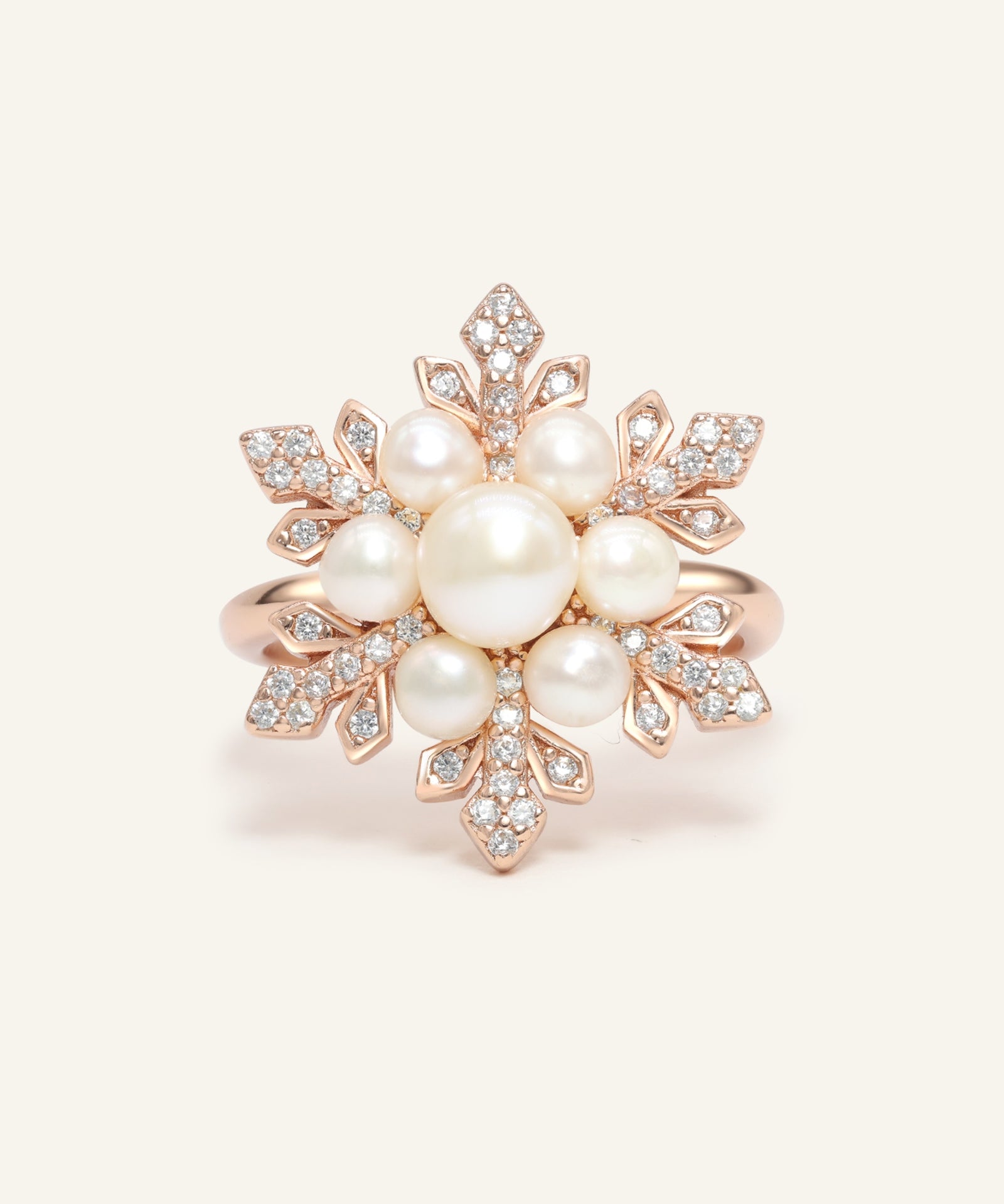 Close-up of the Snowflake Pearl Halo Ring in rose gold, resting on a warm linen background