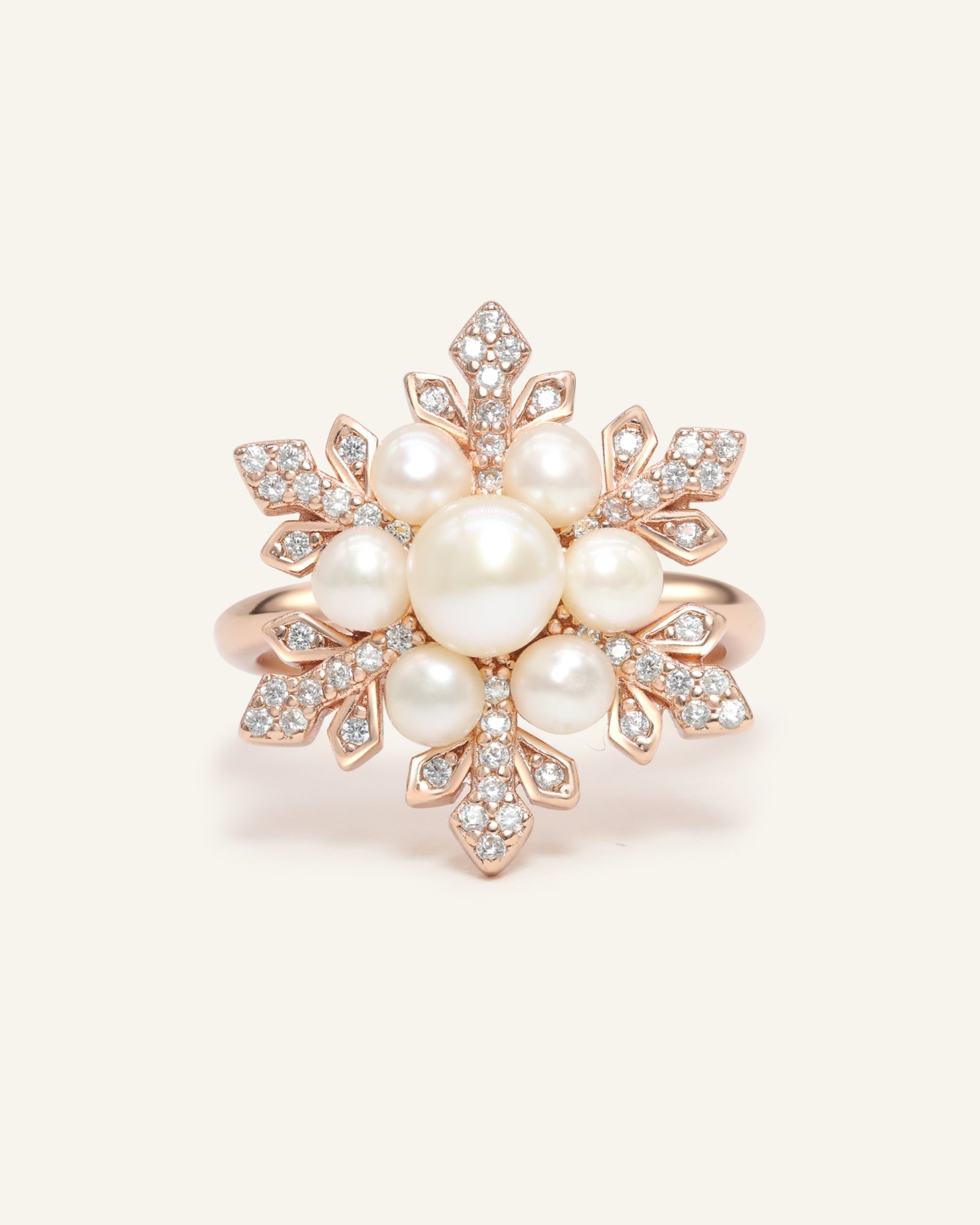 Close-up of the Snowflake Pearl Halo Ring in rose gold, resting on a warm linen background