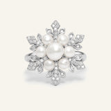 Snowflake Pearl Halo Ring in silver, resting on a warm linen background