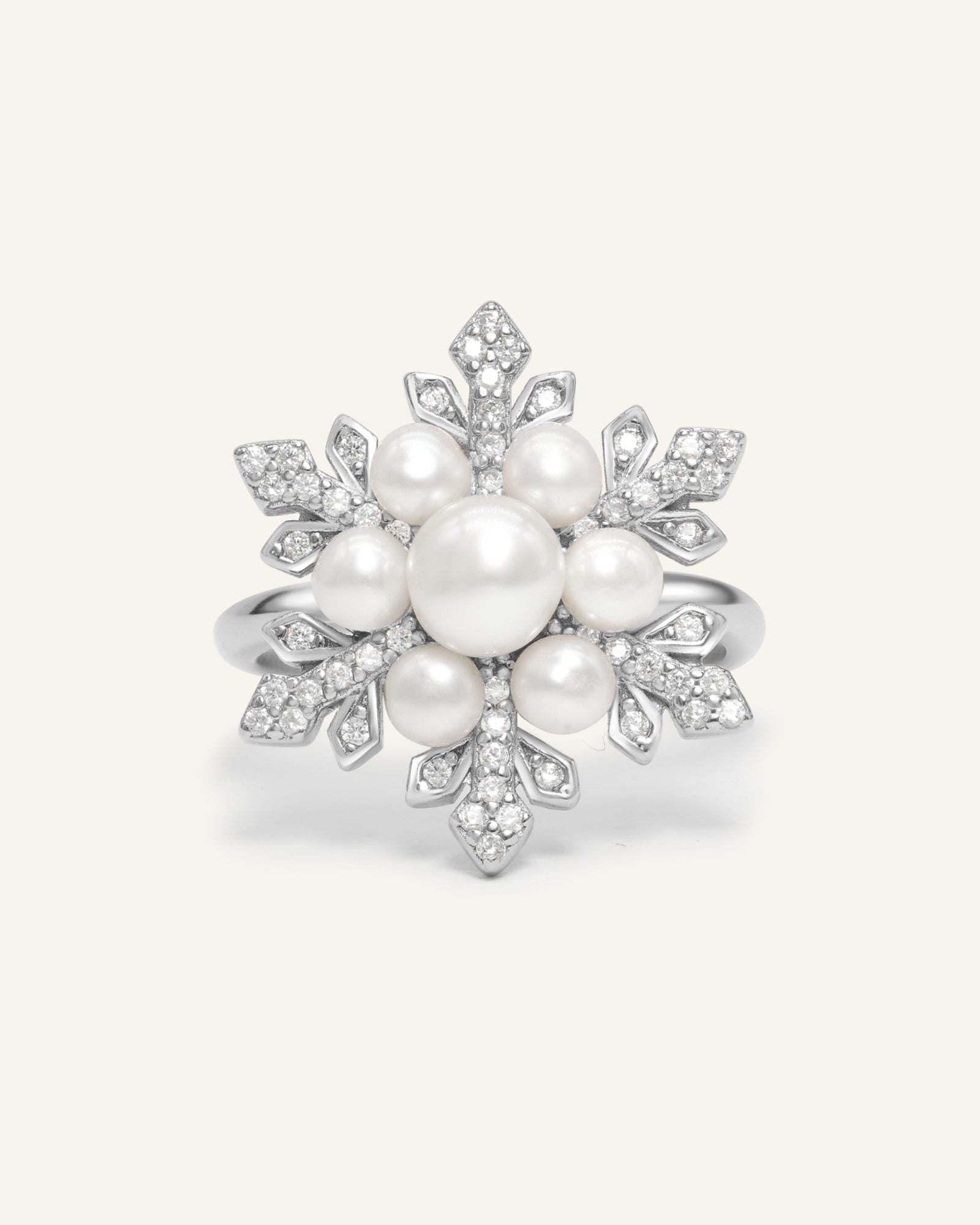 Snowflake Pearl Halo Ring in silver, resting on a warm linen background