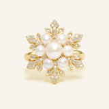 Snowflake Pearl Halo Ring in yellow gold, resting on a warm linen background