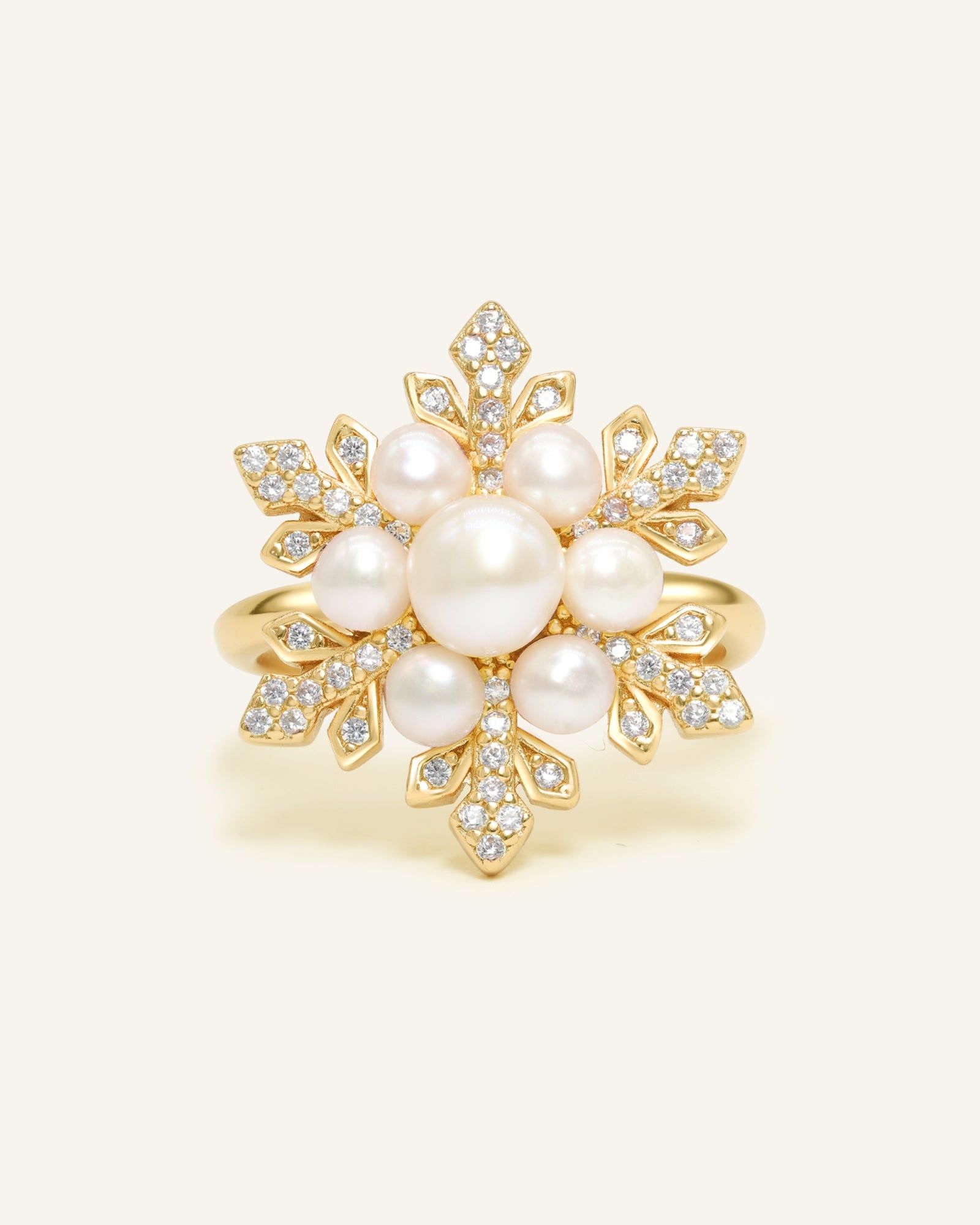 Snowflake Pearl Halo Ring in yellow gold, resting on a warm linen background