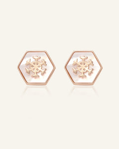 Close-up of the Snowflake Mother of Pearl Studs in rose gold, resting on a warm linen background
