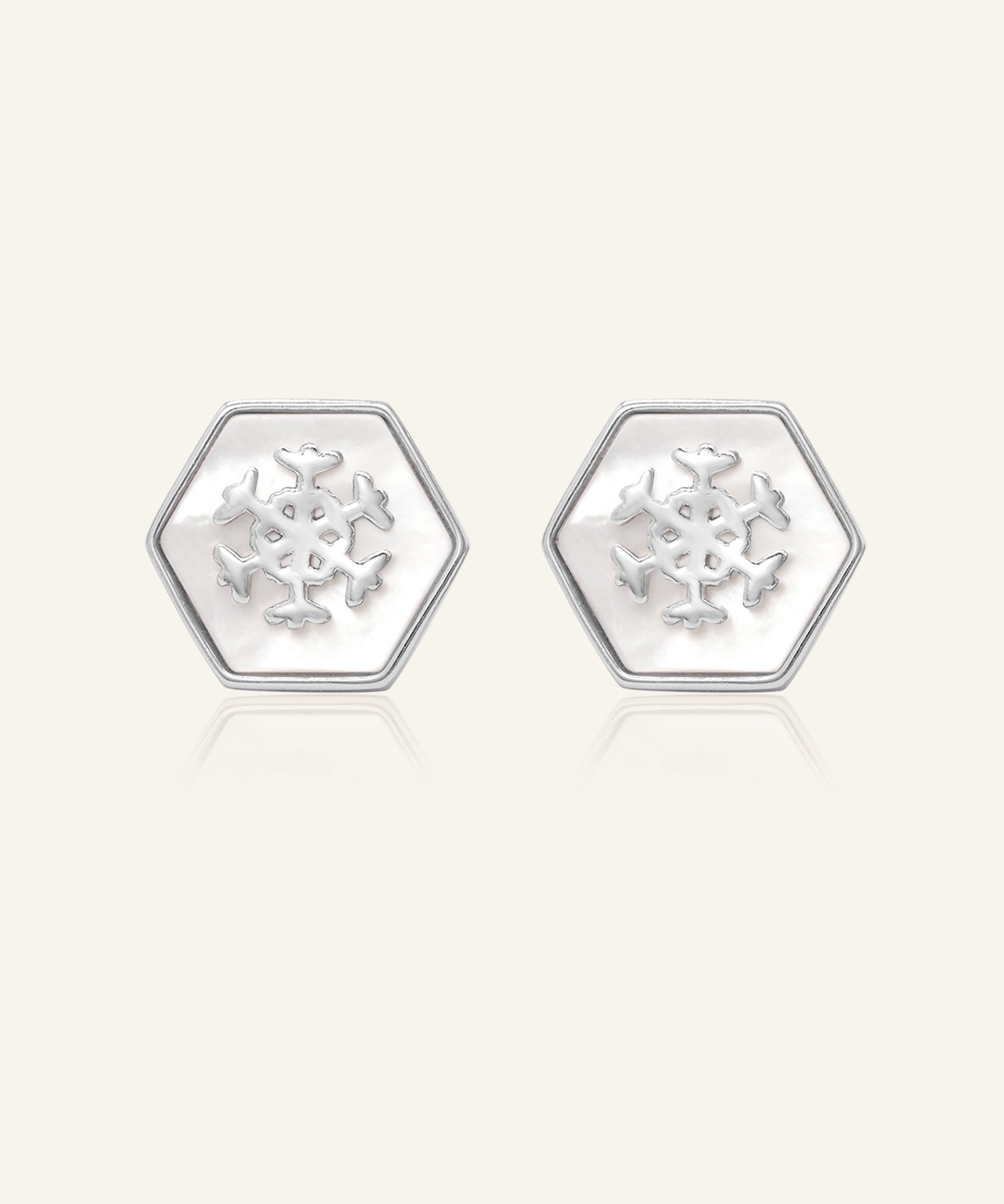 Snowflake Mother of Pearl Studs in silver, resting on a warm linen background