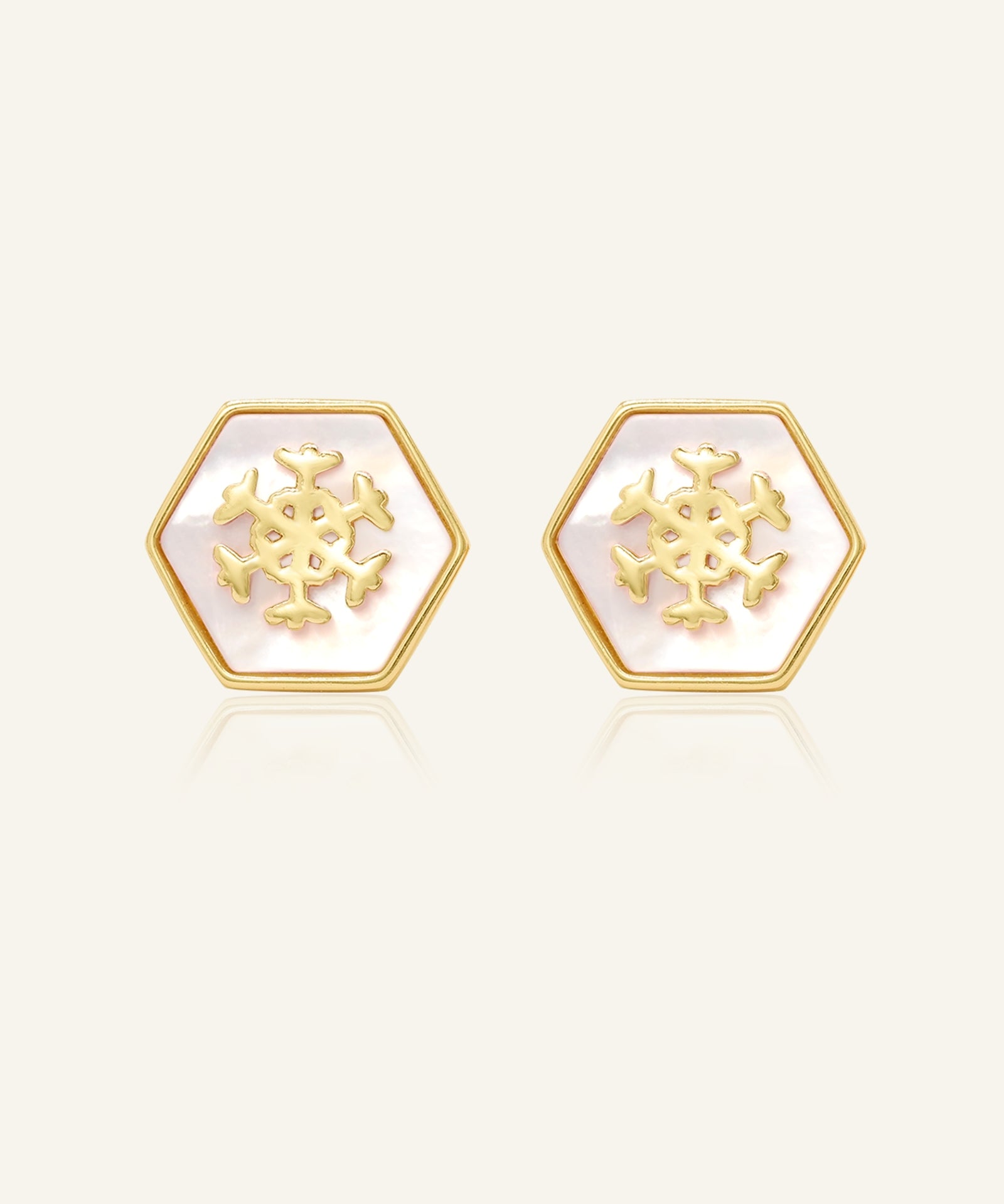 Snowflake Mother of Pearl Studs in yellow gold, resting on a warm linen background