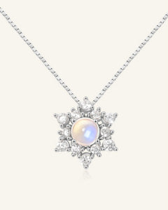 Close-up of the Snowflake Moonstone Necklace in silver, resting on a warm linen background