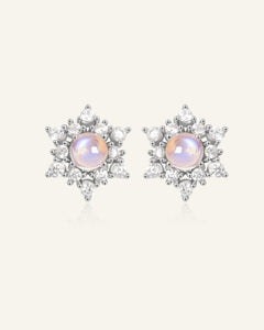 Close-up of the Snowflake Moonstone Studs in silver, resting on a warm linen background