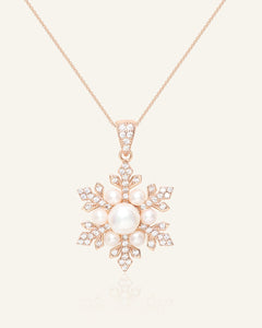 Close-up of the Snowflake Pearl Halo Necklace in rose gold, resting on a warm linen background