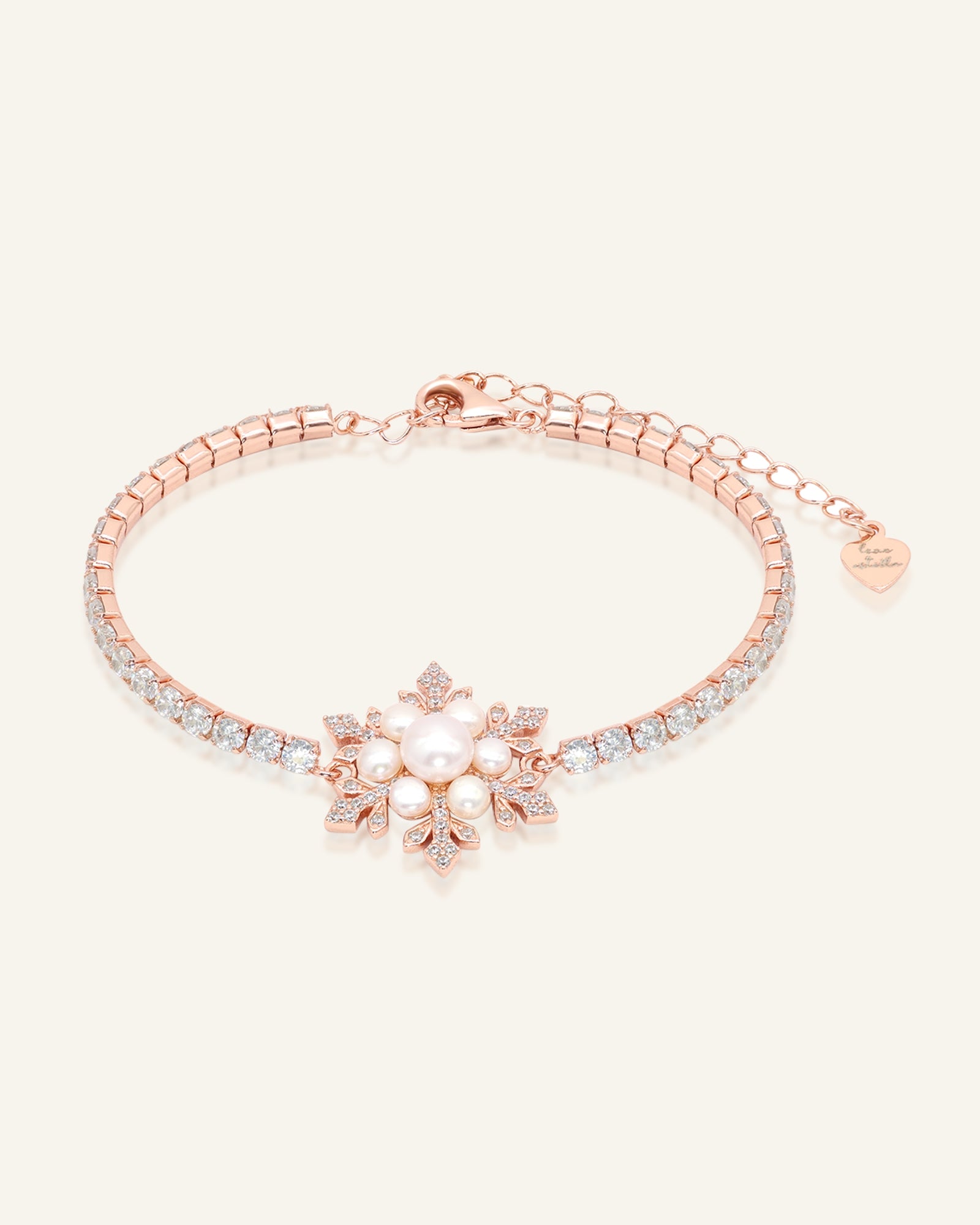 Close-up of the Snowflake Pearl Tennis Bracelet in rose gold, resting on a warm linen background