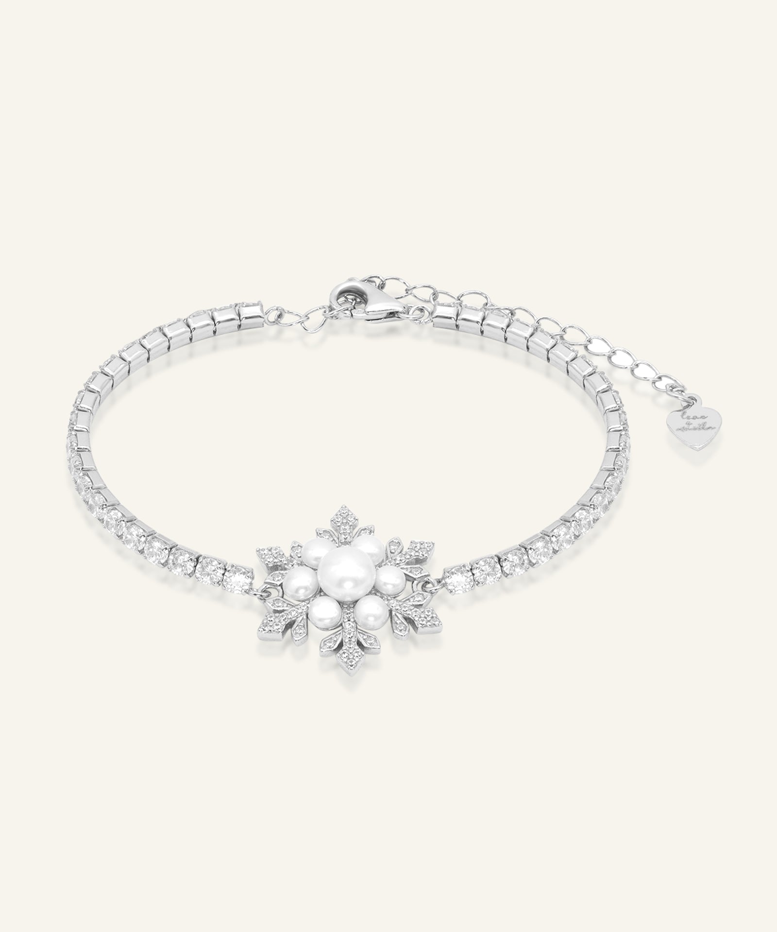 Snowflake Pearl Tennis Bracelet in silver, resting on a warm linen background