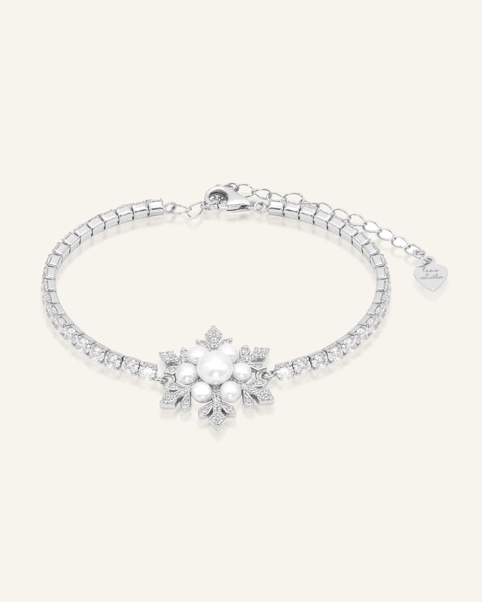 Snowflake Pearl Tennis Bracelet in silver, resting on a warm linen background