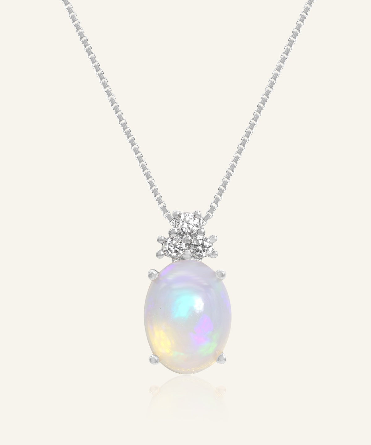 Solace Opal Necklace in silver, resting on a warm linen background