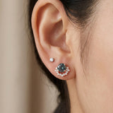 Model wearing 18k rose gold Starlight Crown Crescent Moissanite Stud in Celestial Teal in lower ear lobe piercing next to a clear solitaire stud.