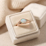 Supernova Signet Opal Ring in rose gold, laid flat on a tabletop