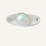 Supernova Signet Opal Ring in silver, resting on a warm linen background
