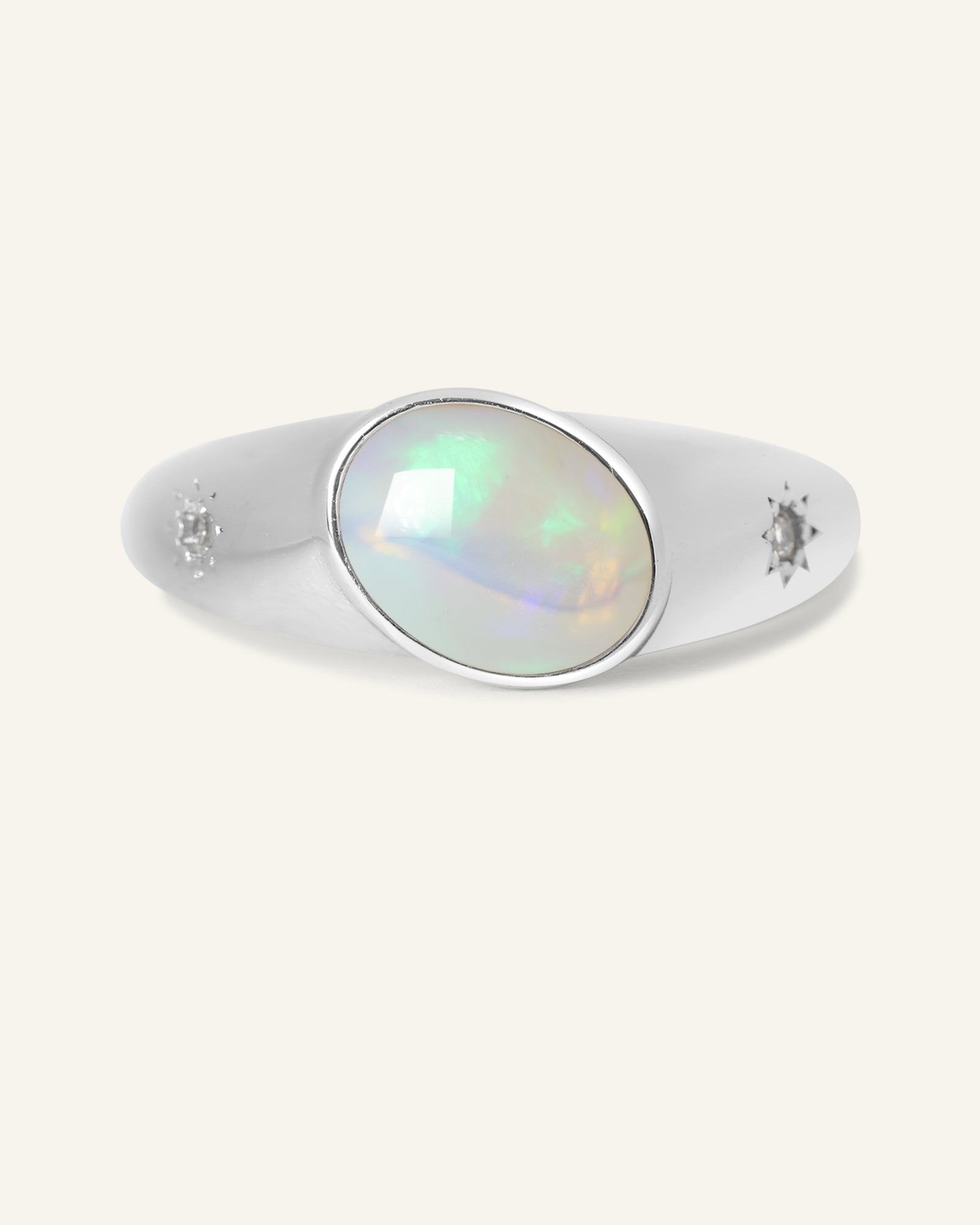 Supernova Signet Opal Ring in silver, resting on a warm linen background